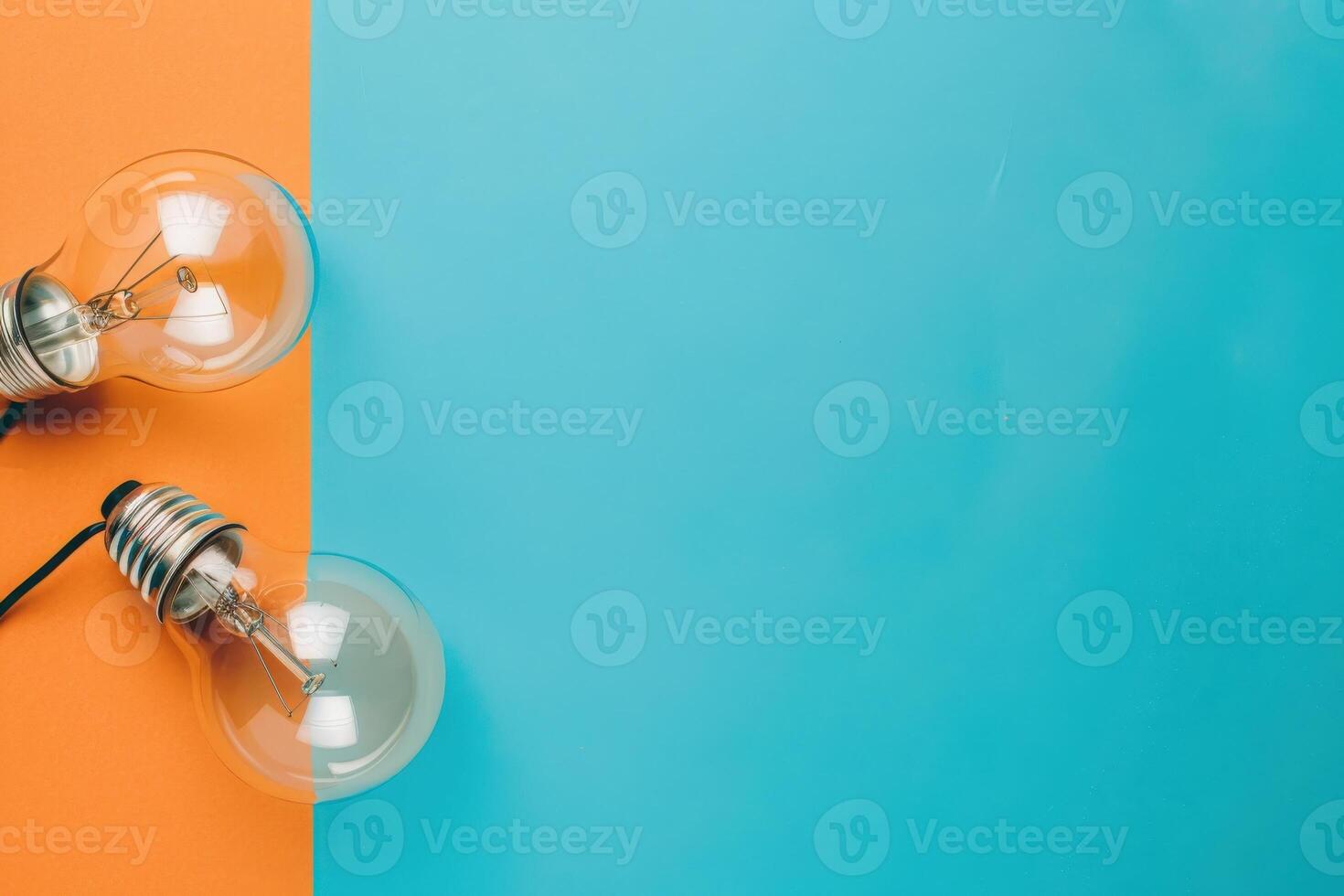 Two light bulbs rest on a split background of orange and turquoise, showcasing innovative energy-saving tips in a visually striking manner. photo