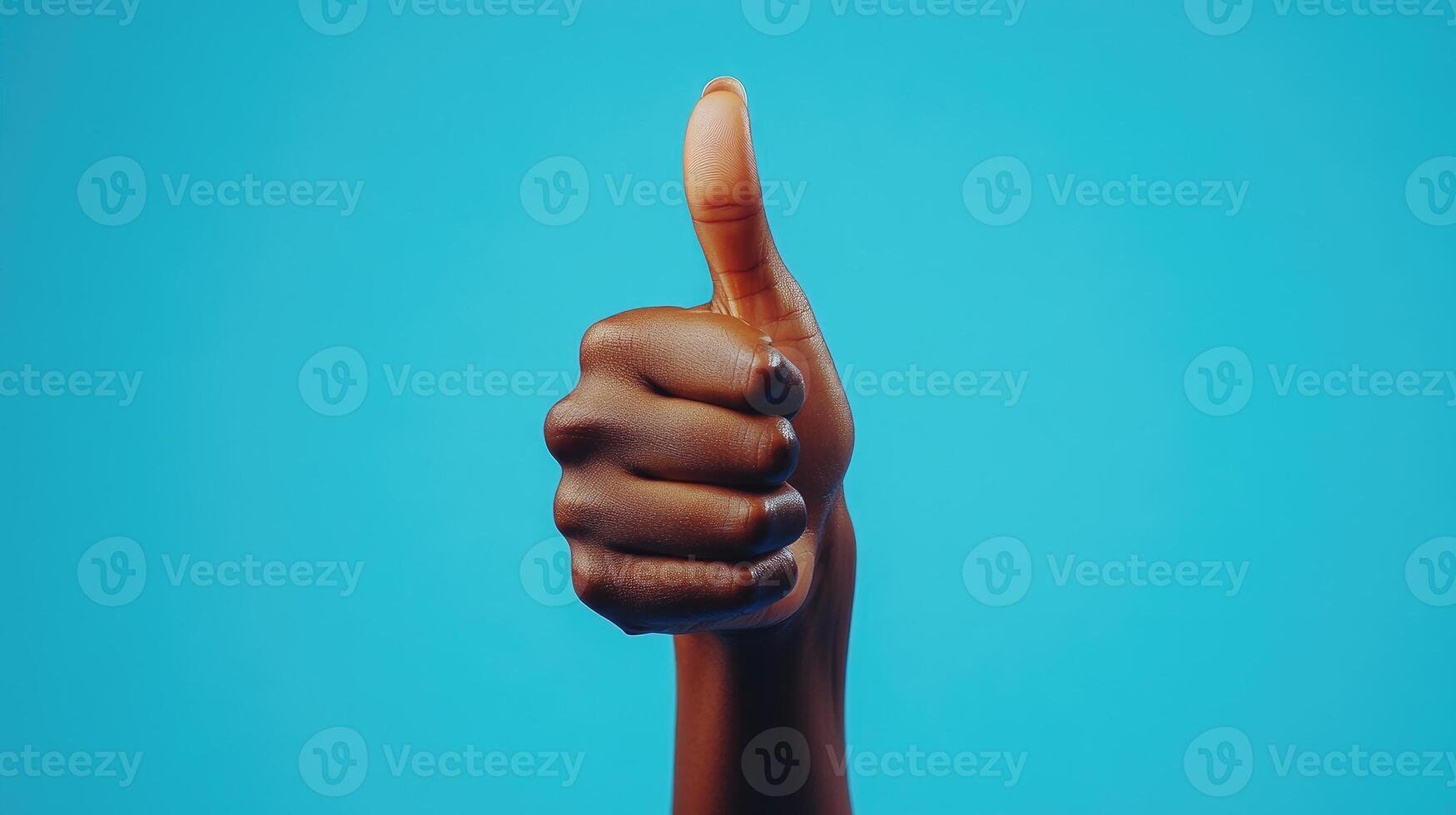 A Person's Hand Giving a Thumbs Up Gesture Against a Blue Background photo
