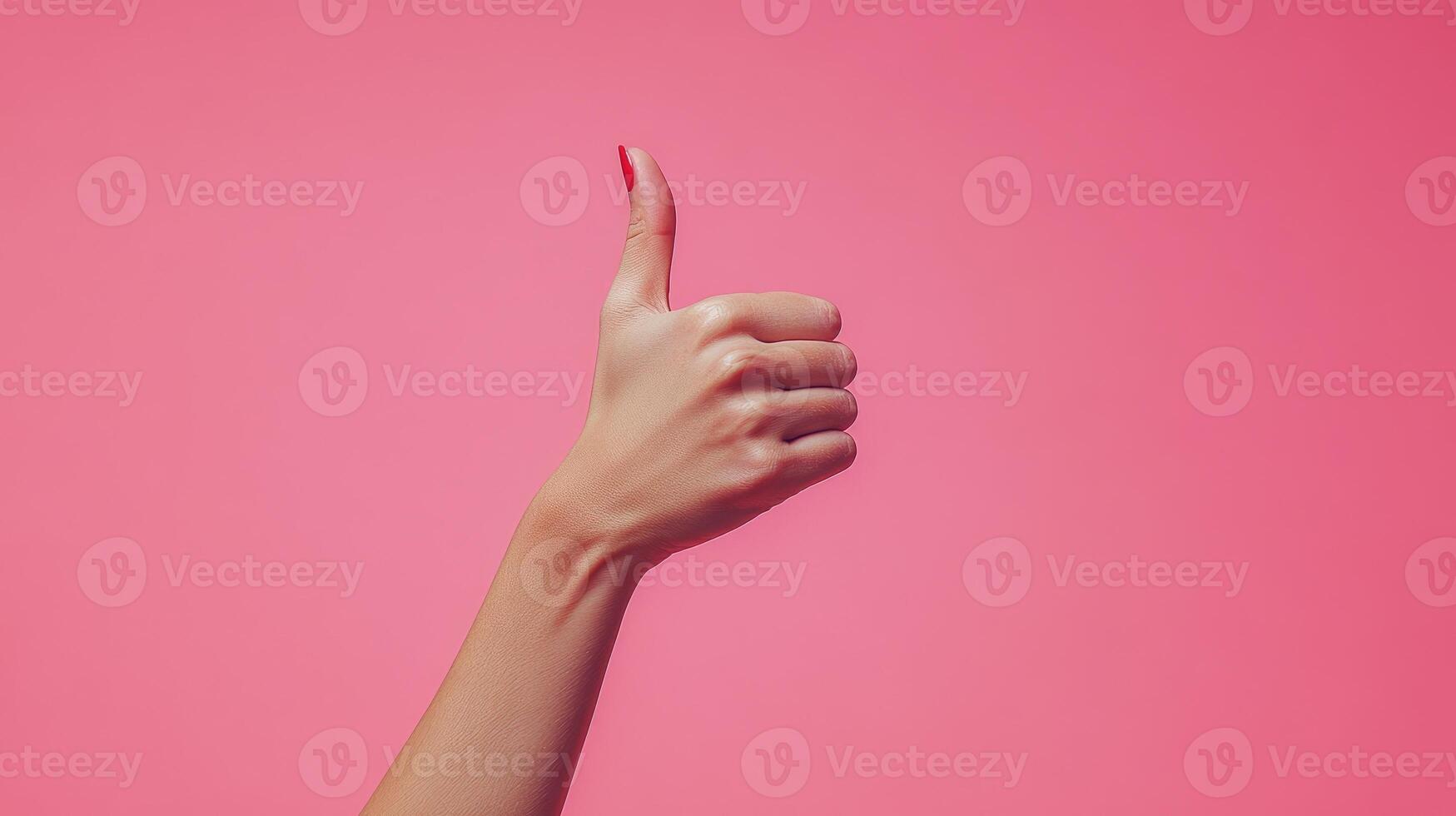 A Hand with Red Nail Polish Giving a Thumbs Up Gesture Against a Pink Background photo