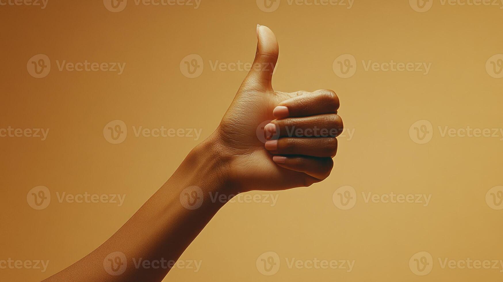 A Hand Giving a Thumbs Up Gesture Against a Tan Background photo
