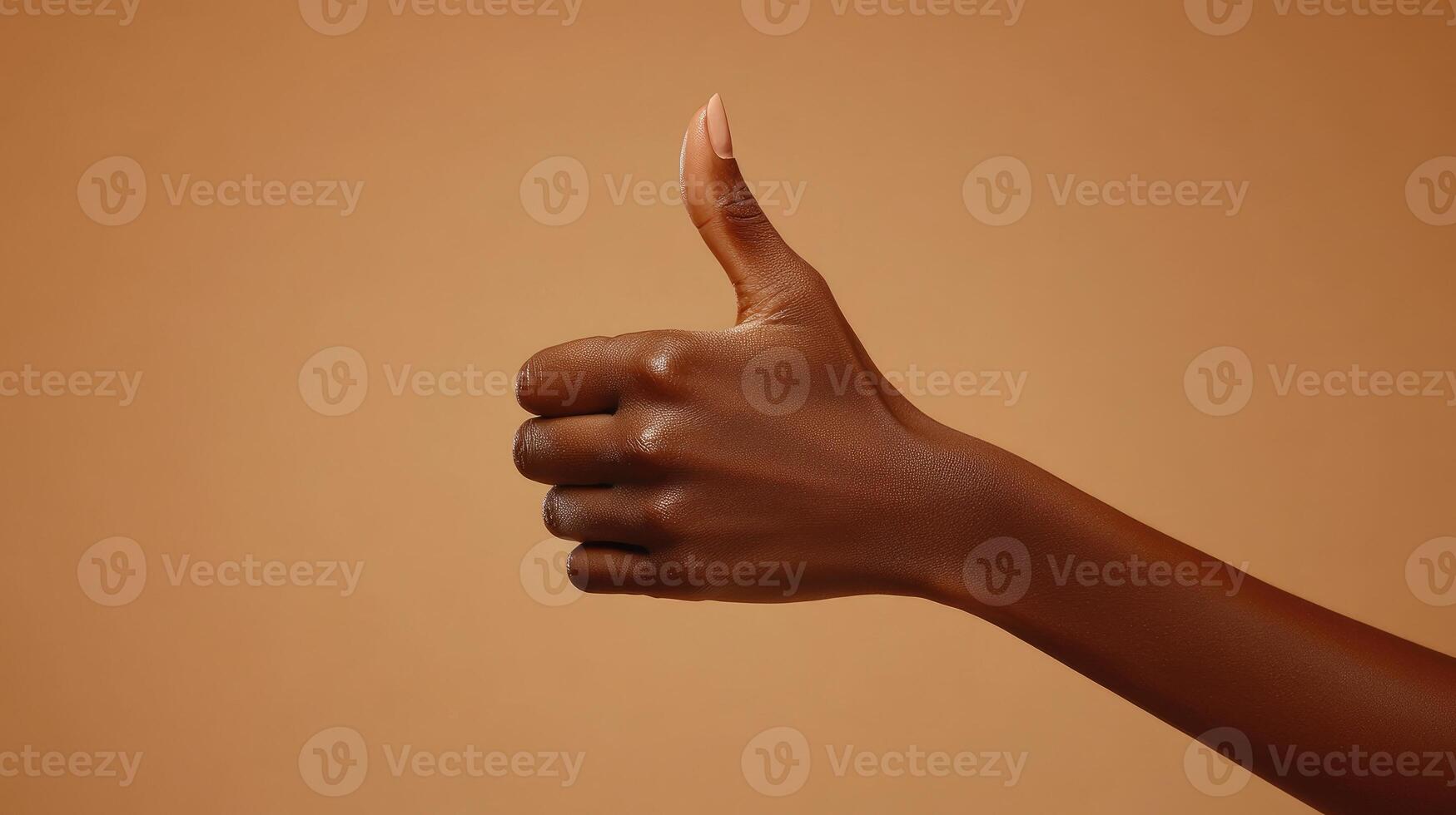 A Hand Giving a Thumbs Up Gesture Against a Tan Background photo