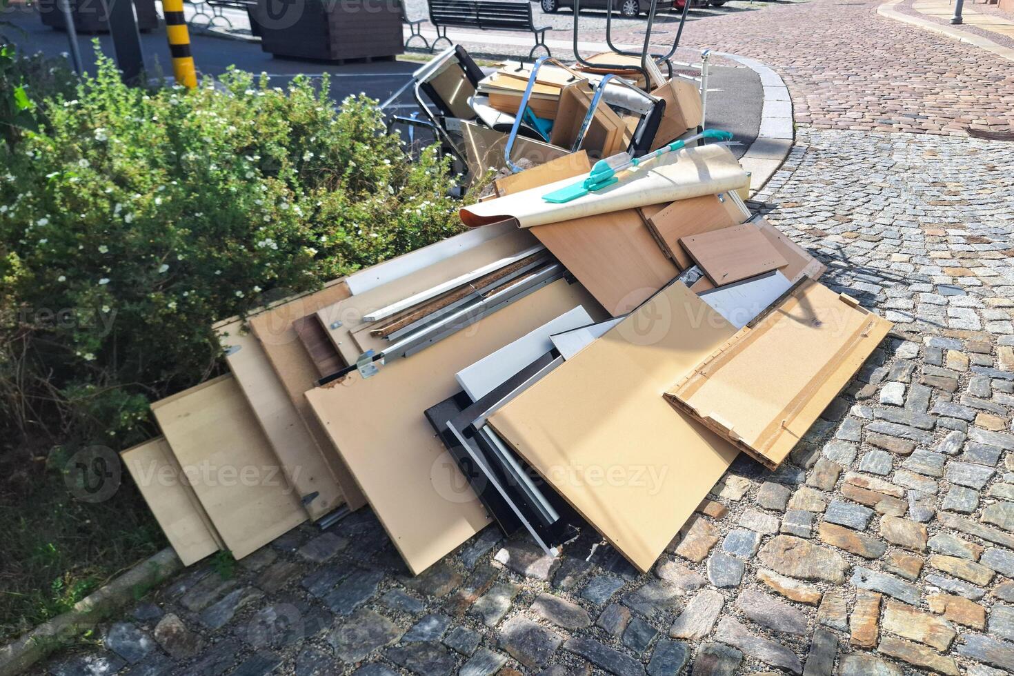 A heap of assorted discarded household items and furniture piled up on a cobblestone street, depicting a bulk waste collection day in an urban environment. photo
