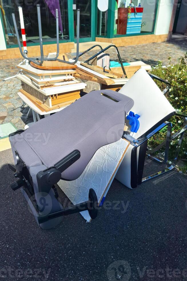 A heap of assorted discarded household items and furniture piled up on a cobblestone street, depicting a bulk waste collection day in an urban environment. photo