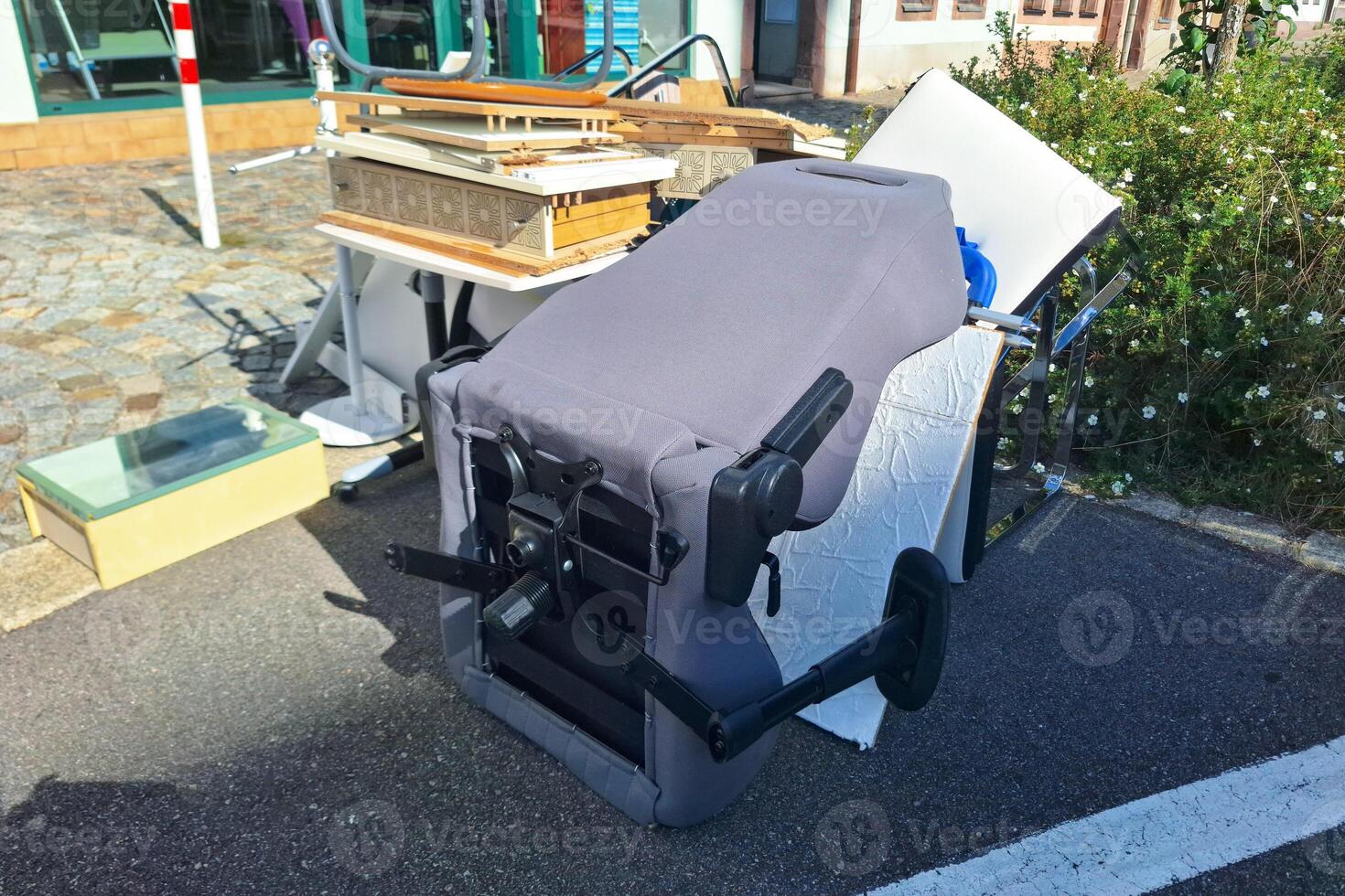 A heap of assorted discarded household items and furniture piled up on a cobblestone street, depicting a bulk waste collection day in an urban environment. photo
