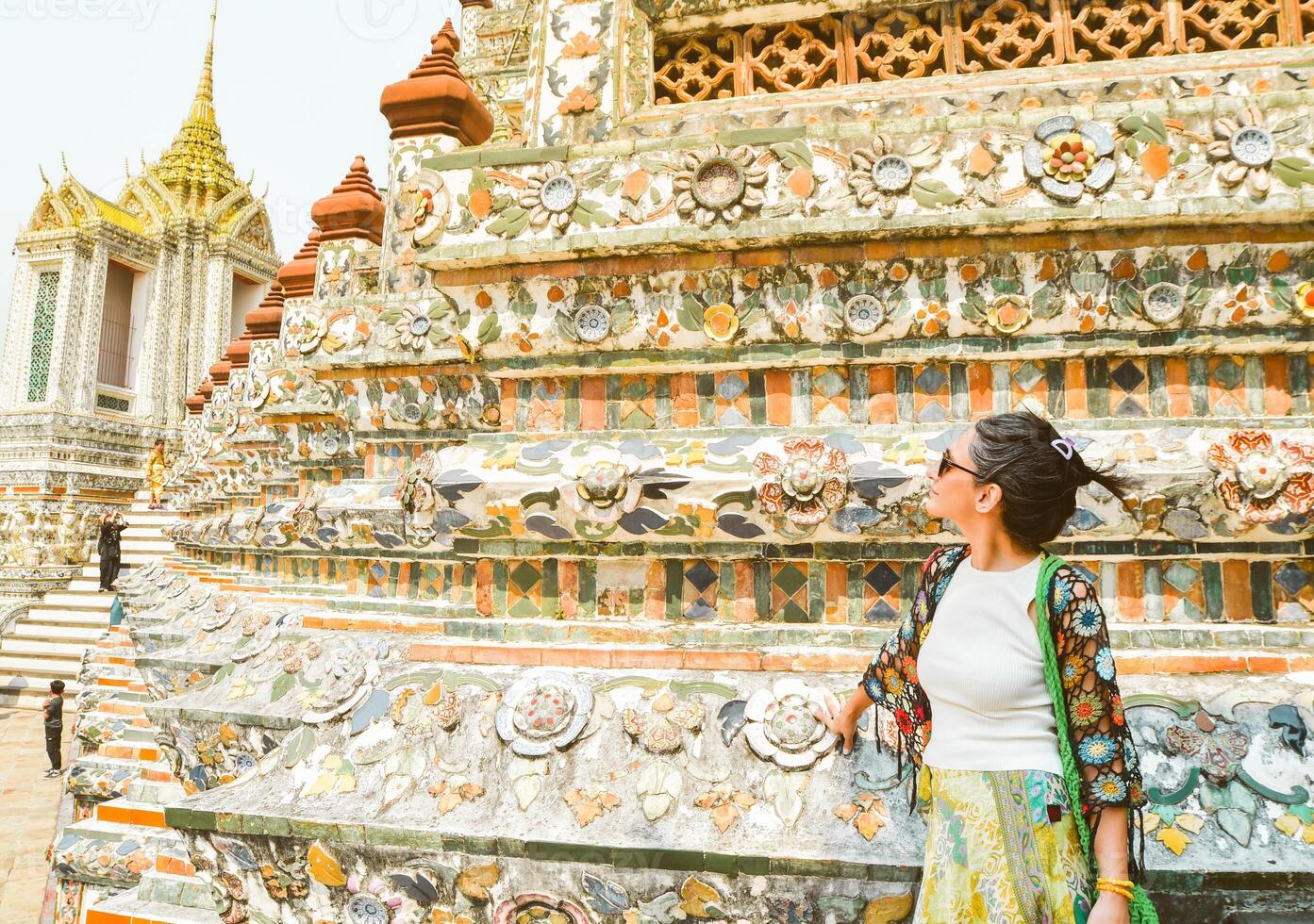 Young woman traveler blogger pose by beautiful famous buddhist temple Wat Arun - famous travel destination in Bangkok, Thailand. Tourist sightseeing south-east asia historical landmarks photo