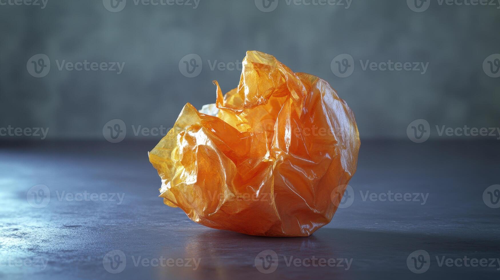 Crumpled orange plastic wrapper on a textured surface indoors in soft lighting photo