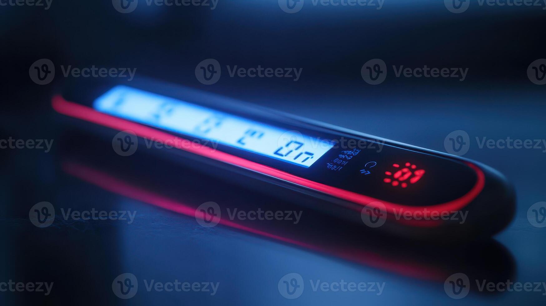A futuristic digital measuring device illuminated by blue and red lights on a reflective surface at night photo