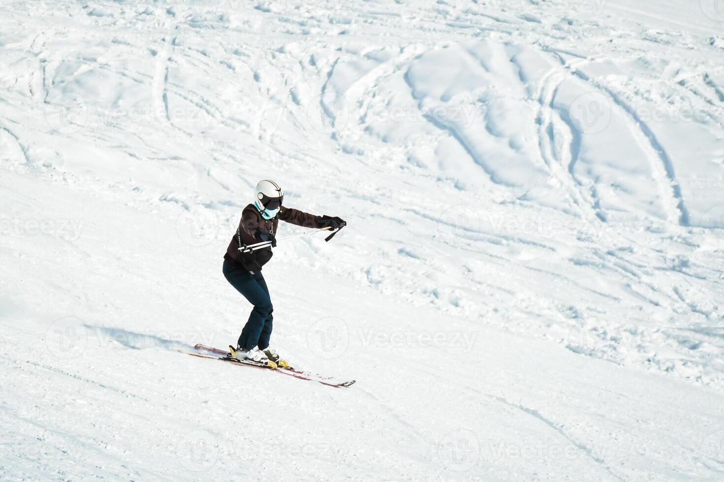 Female beginner woman practice skiing downhill hold pole ahead to keep balance on white slope in mountains ski resort downhill isolated. Learn to ski in alps europe photo