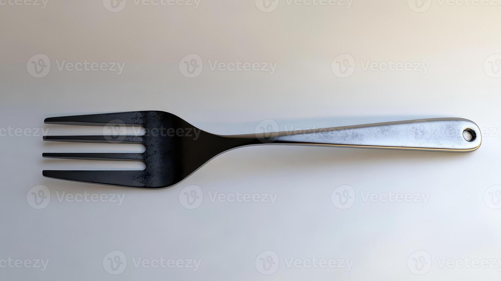 A metallic three-pronged fork lying flat against a white background photo