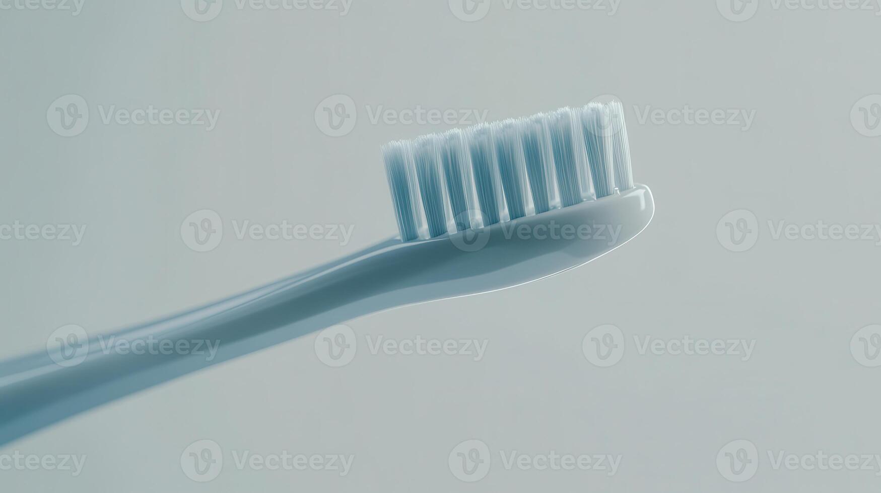 Close-up of a soft-bristled toothbrush against a light gray background, perfect for dental hygiene routines photo