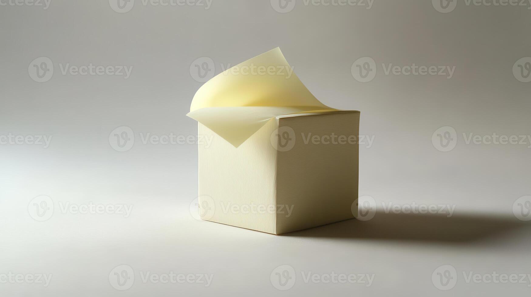 A plain cream-colored cube with a slightly curled yellow note sticking out on a neutral background in soft light photo