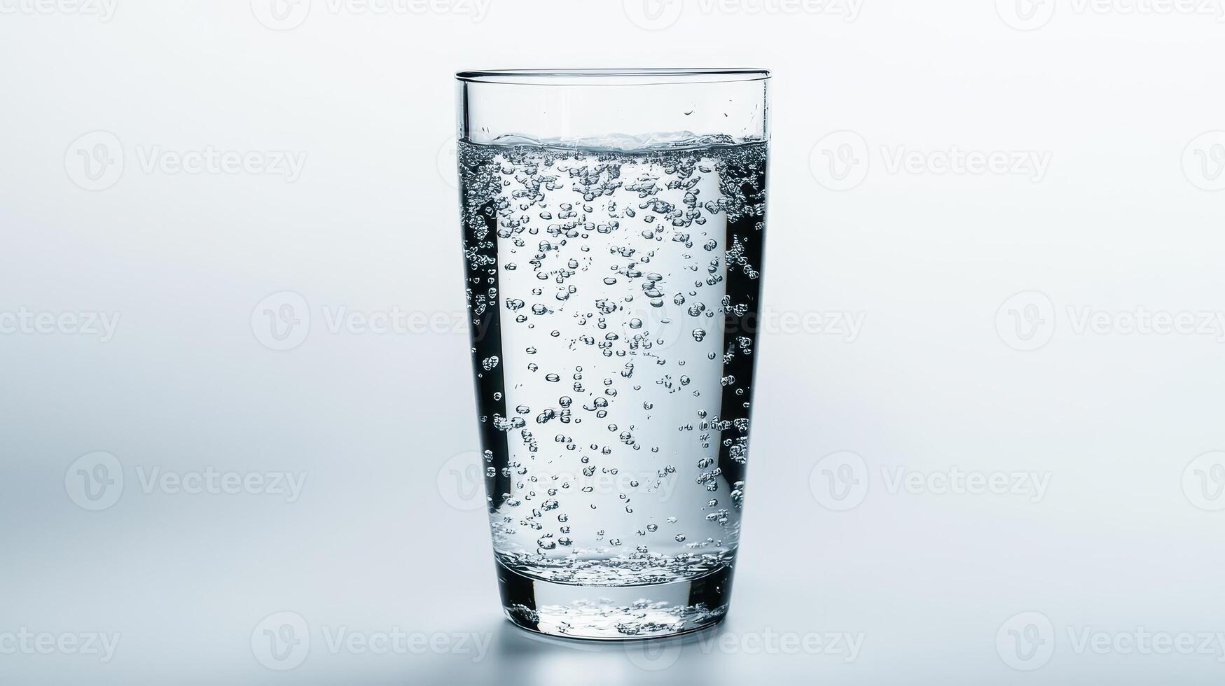 Clear glass filled with sparkling water against a light background photo