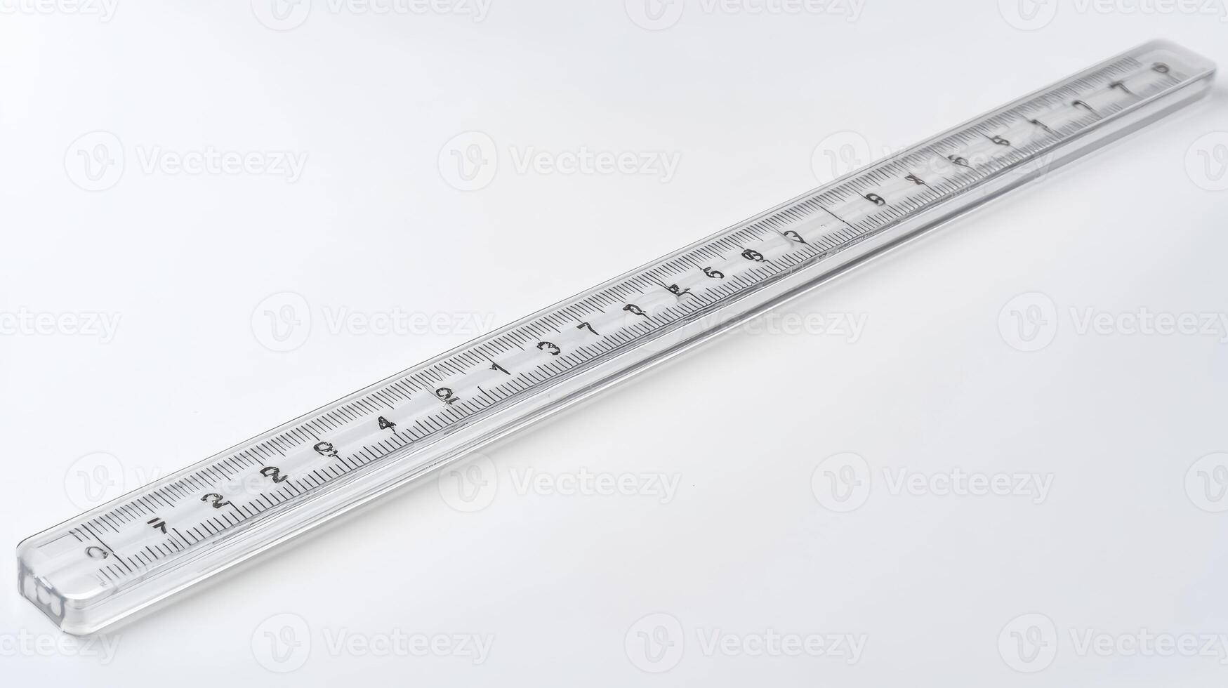 Clear plastic ruler lying on a white surface with measuring markings along its length photo