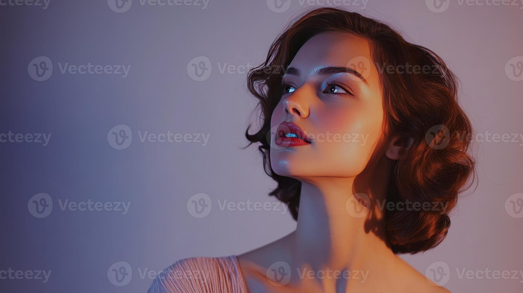 Young woman with short curly hair poses elegantly against a softly lit backdrop during a portrait session photo
