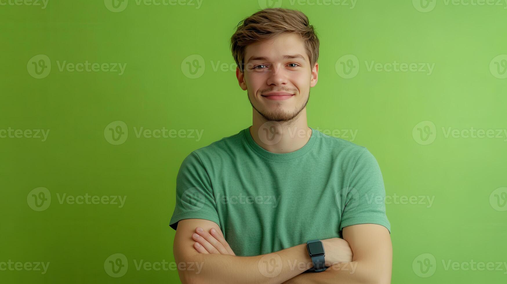 Young man smiling confidently with crossed arms against a bright green background in a casual setting photo