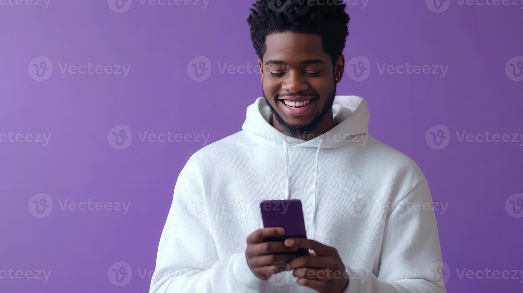 Young man smiling while using a smartphone against a purple background photo