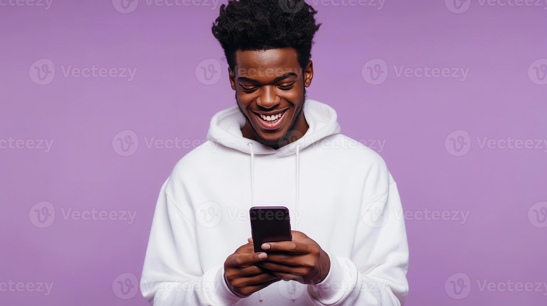Young man smiling while using a smartphone against a purple background in a casual setting photo