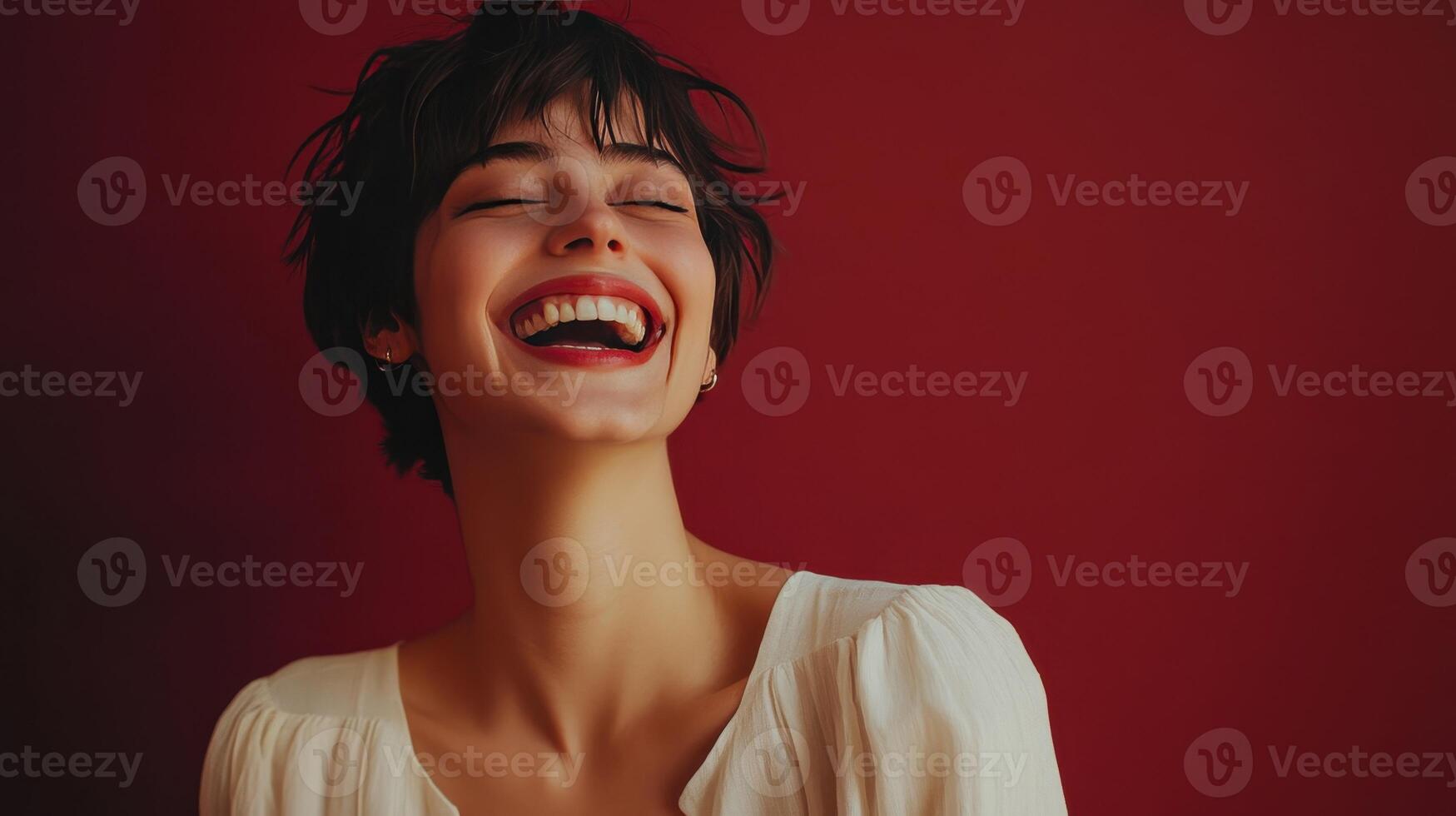 Joyful young woman laughing in front of a red background during a casual indoor photoshoot photo