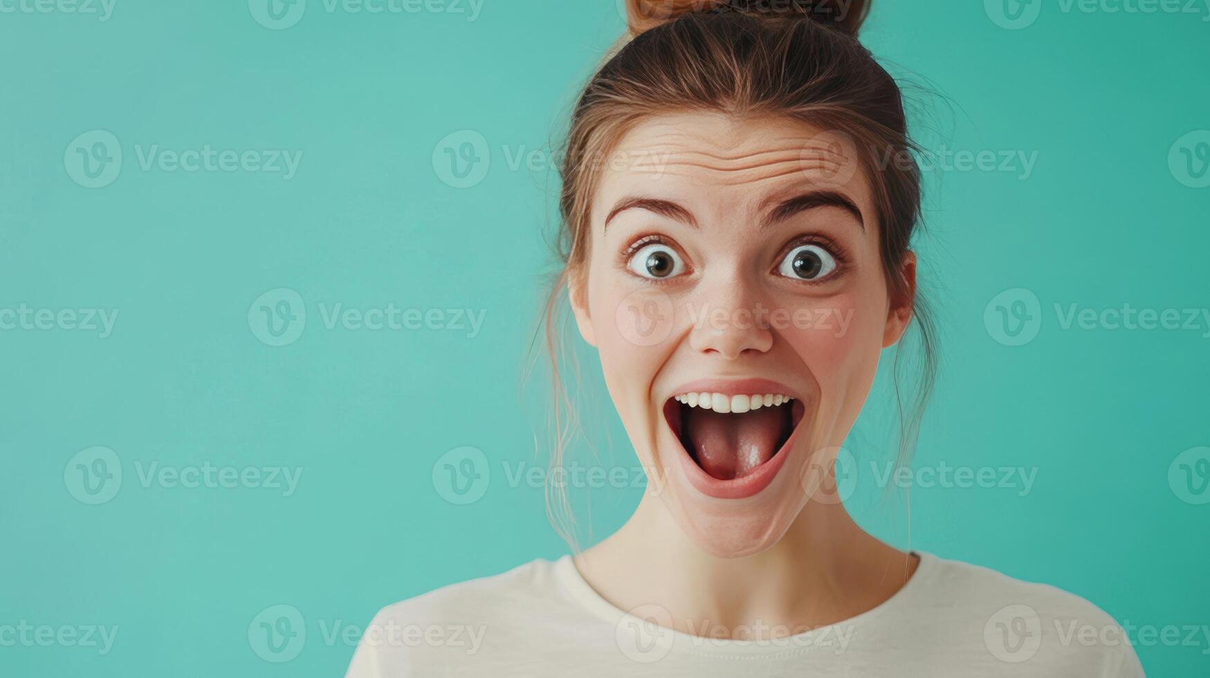 A young woman expressing joy with a big smile against a bright turquoise background photo