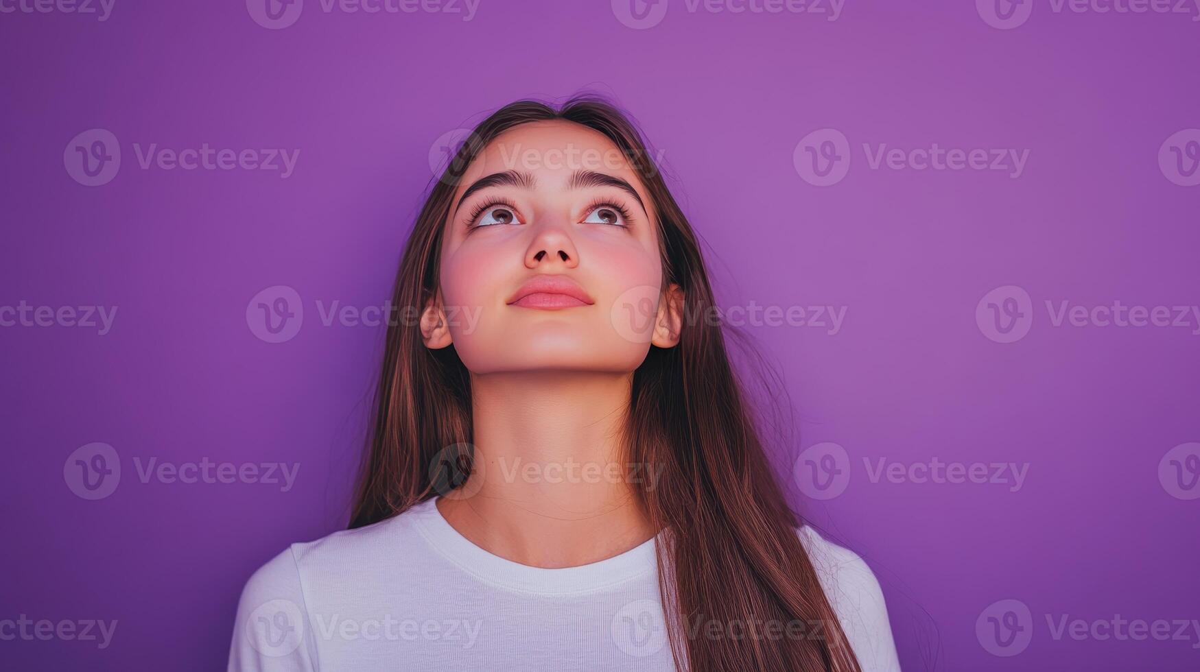 Young woman looking upwards in front of a vibrant purple background, conveying curiosity and contemplation photo