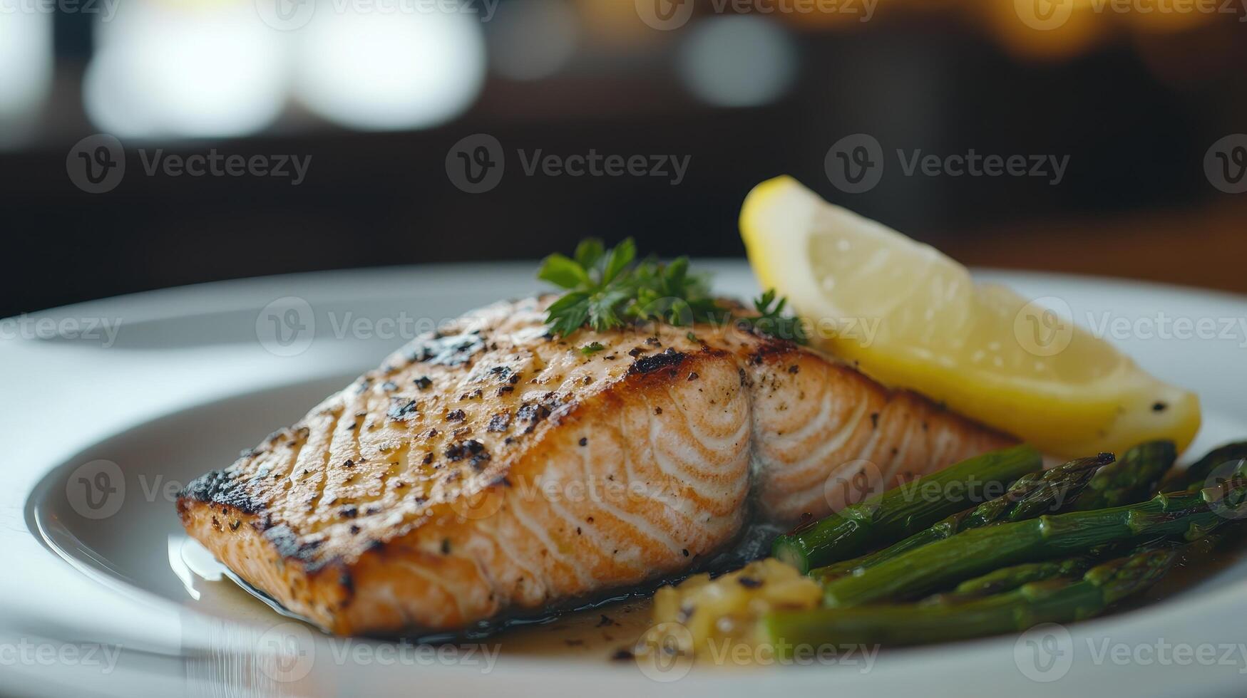 Grilled salmon fillet served with asparagus and lemon wedge on a white plate in a cozy restaurant setting photo