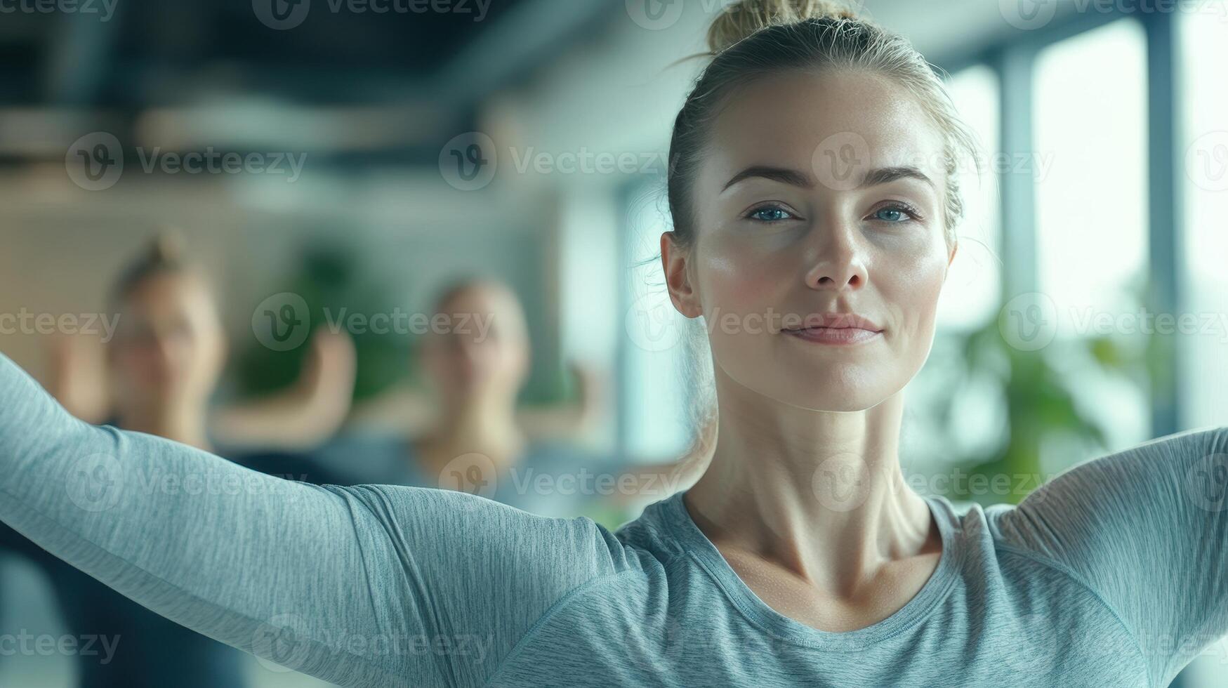 Woman practicing yoga in a bright studio during a morning class with classmates focusing on their postures photo
