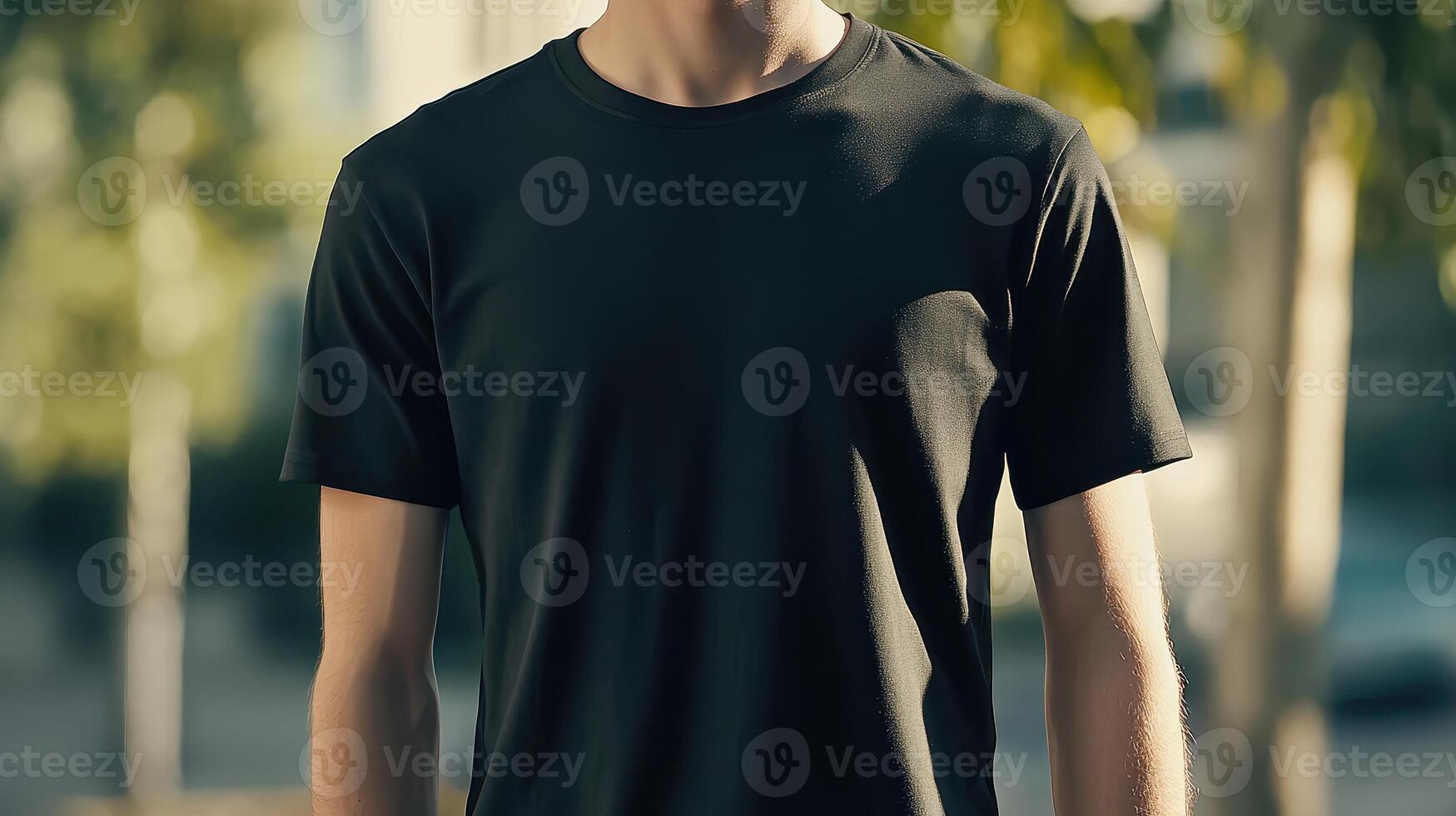 Young man wearing a black t-shirt standing outdoors in natural light on a bright day photo