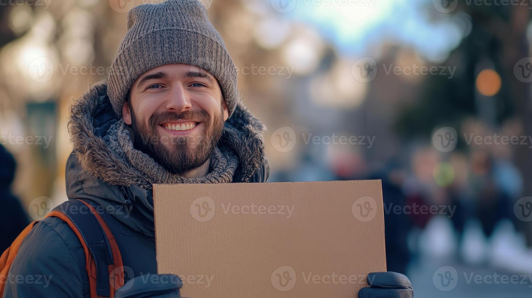 Smiling man holding a blank cardboard sign in a snowy urban environment during winter photo