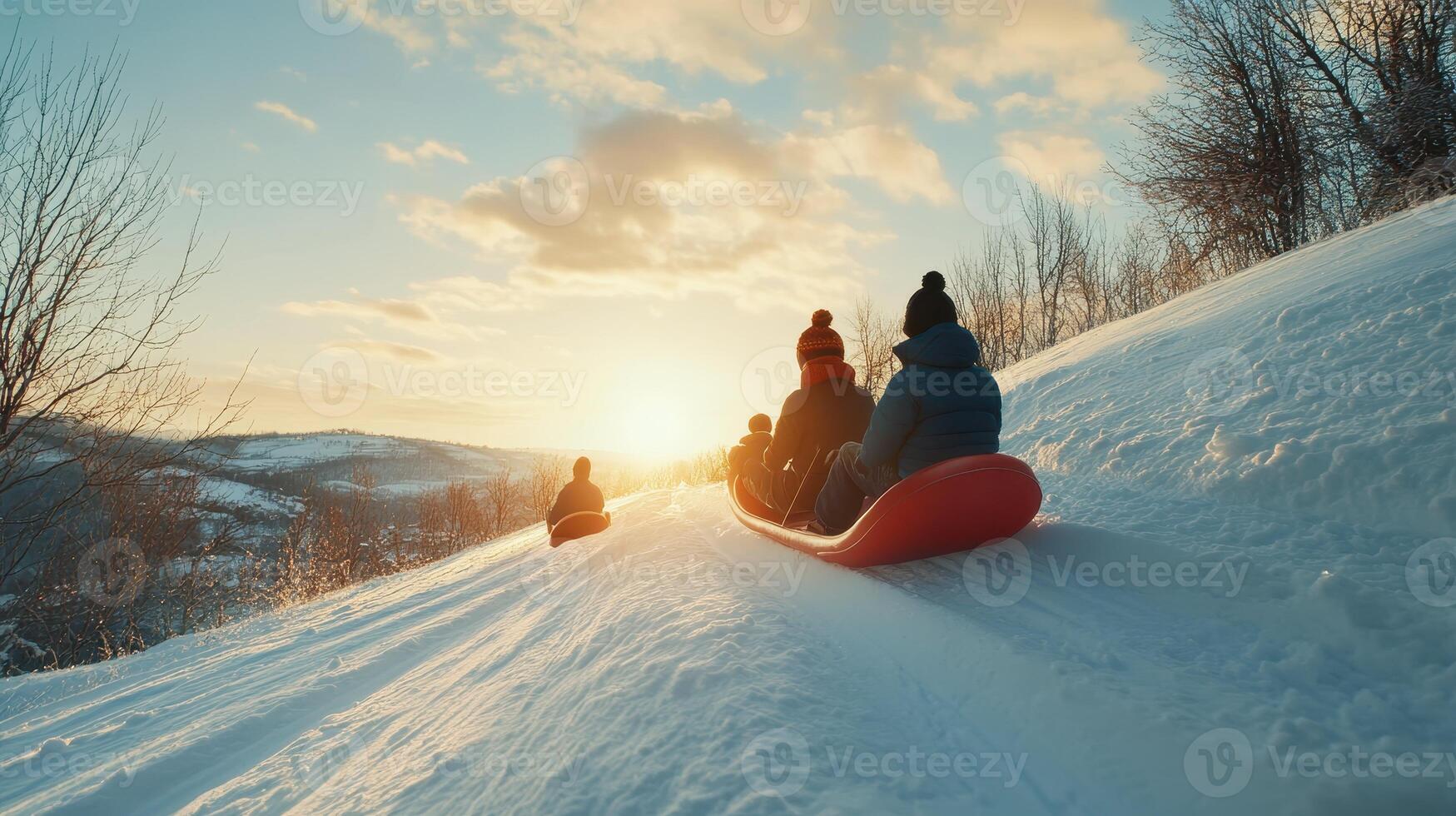 Sledding down a snowy slope at sunset with friends in a winter landscape photo