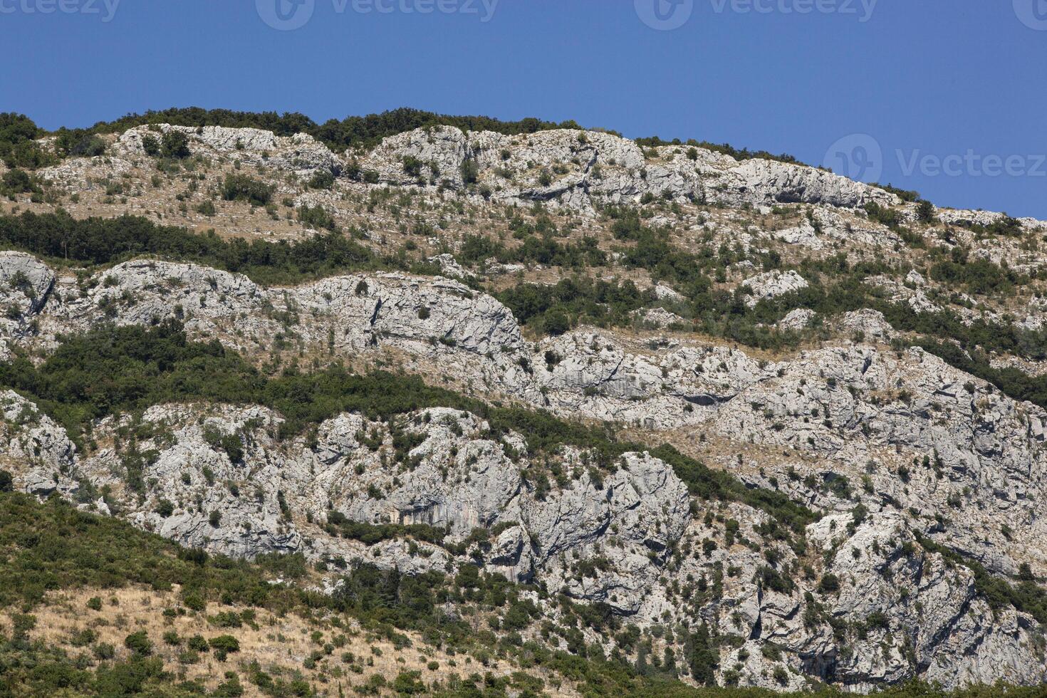Mountain landscape with blue sky and trees. A church stands on top of the mountain. View from above. Horizontal photo