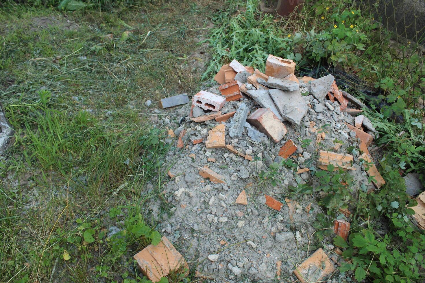 Discarded bricks and concrete on the grass. The problem of disposal of construction waste and residues of building materials photo