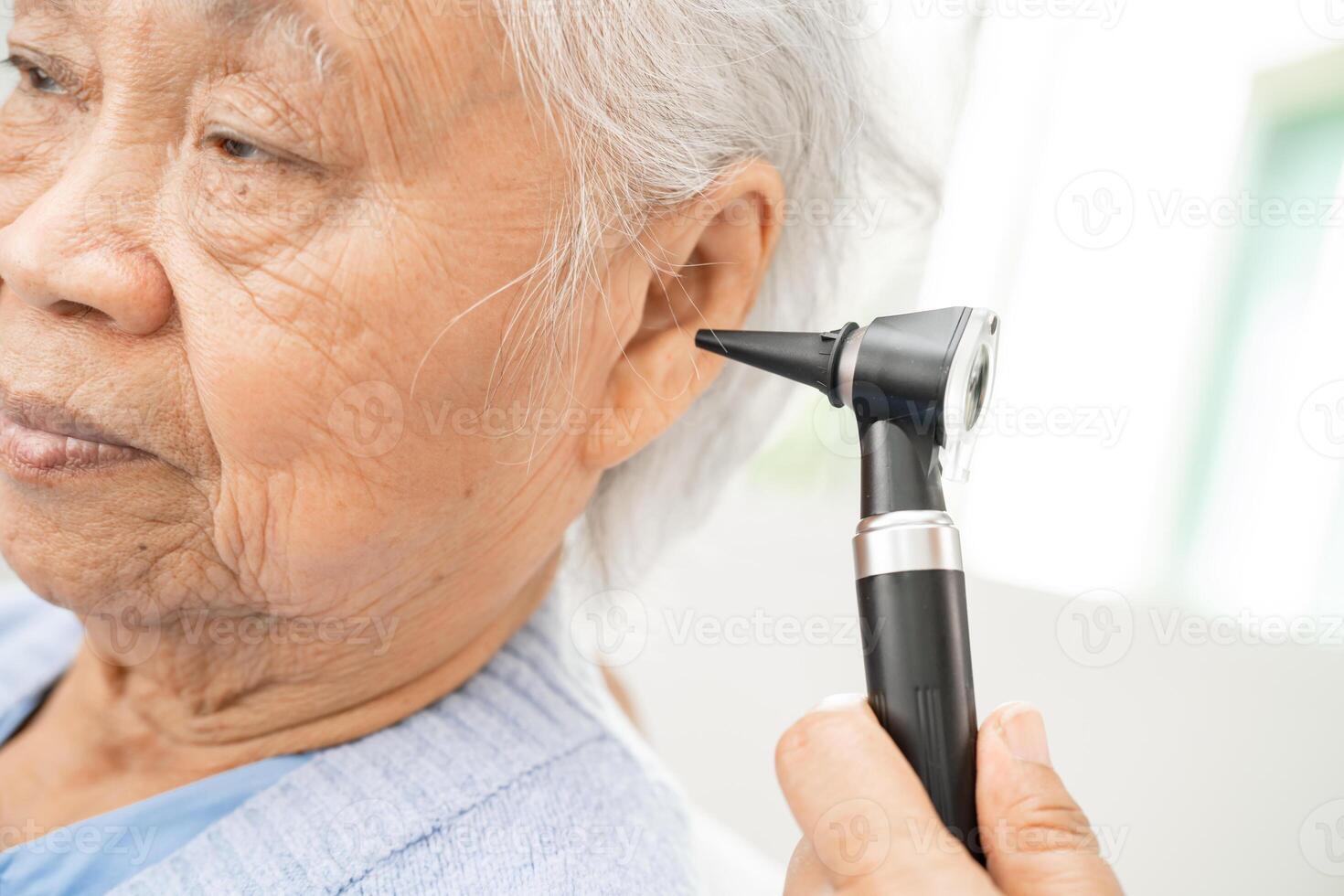 Audiologist or ENT doctor use otoscope checking ear of asian senior woman patient treating hearing loss problem. photo
