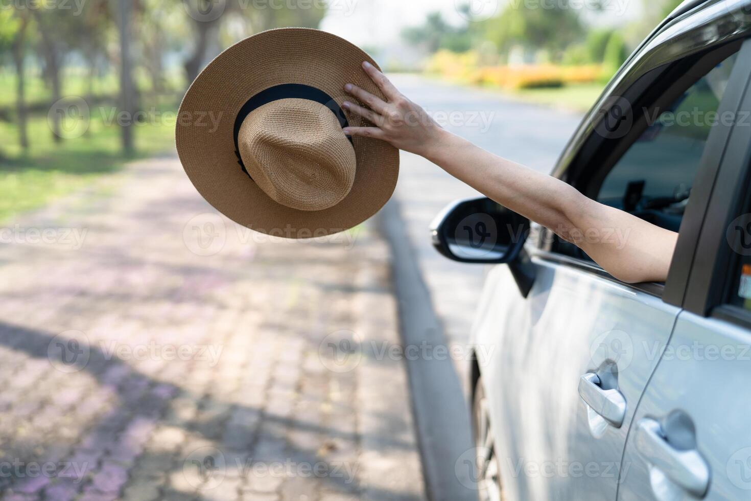 Happy enjoy and freedom in traveling trip with raised hand and holding hat outside of window car in summer vacation holiday. photo