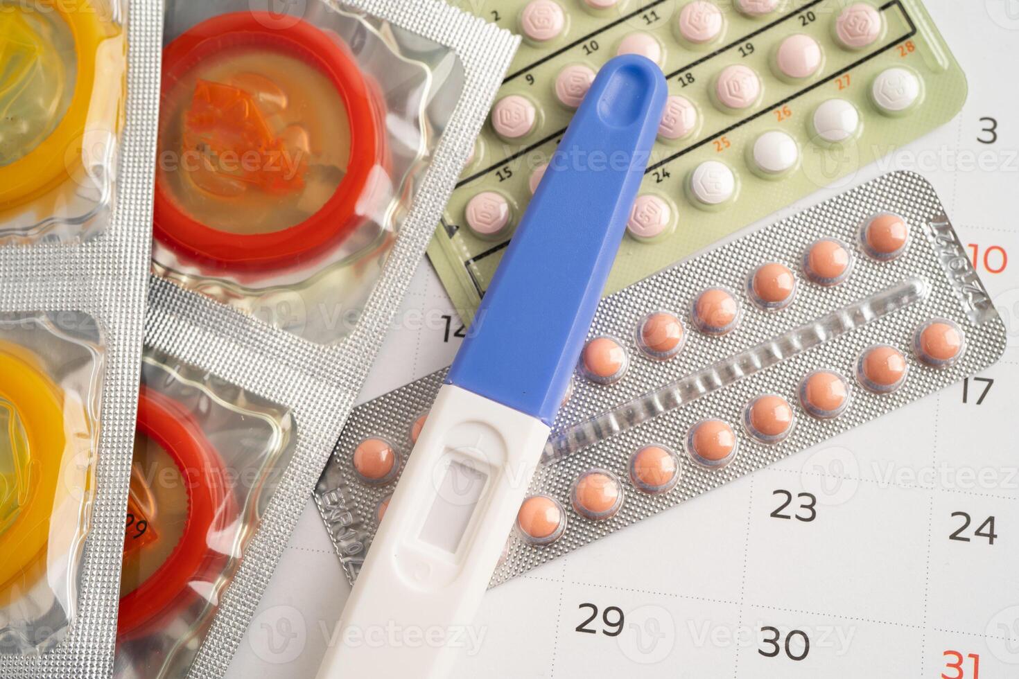Pregnancy test and birth control pills on calendar, contraception health and medicine. photo