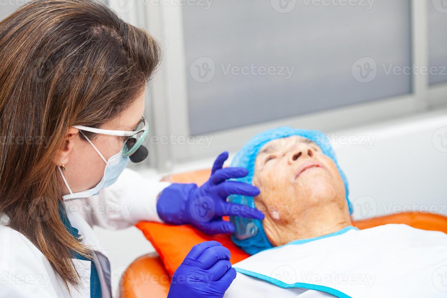 Dermatologist carrying out a skin biopsy on the face of a senior adult patient photo