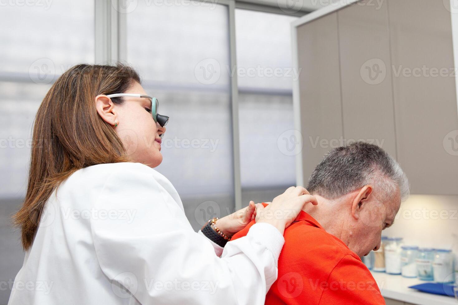 Dermatologist making a routine checkup on a senior male patient using a binocular loupe. photo