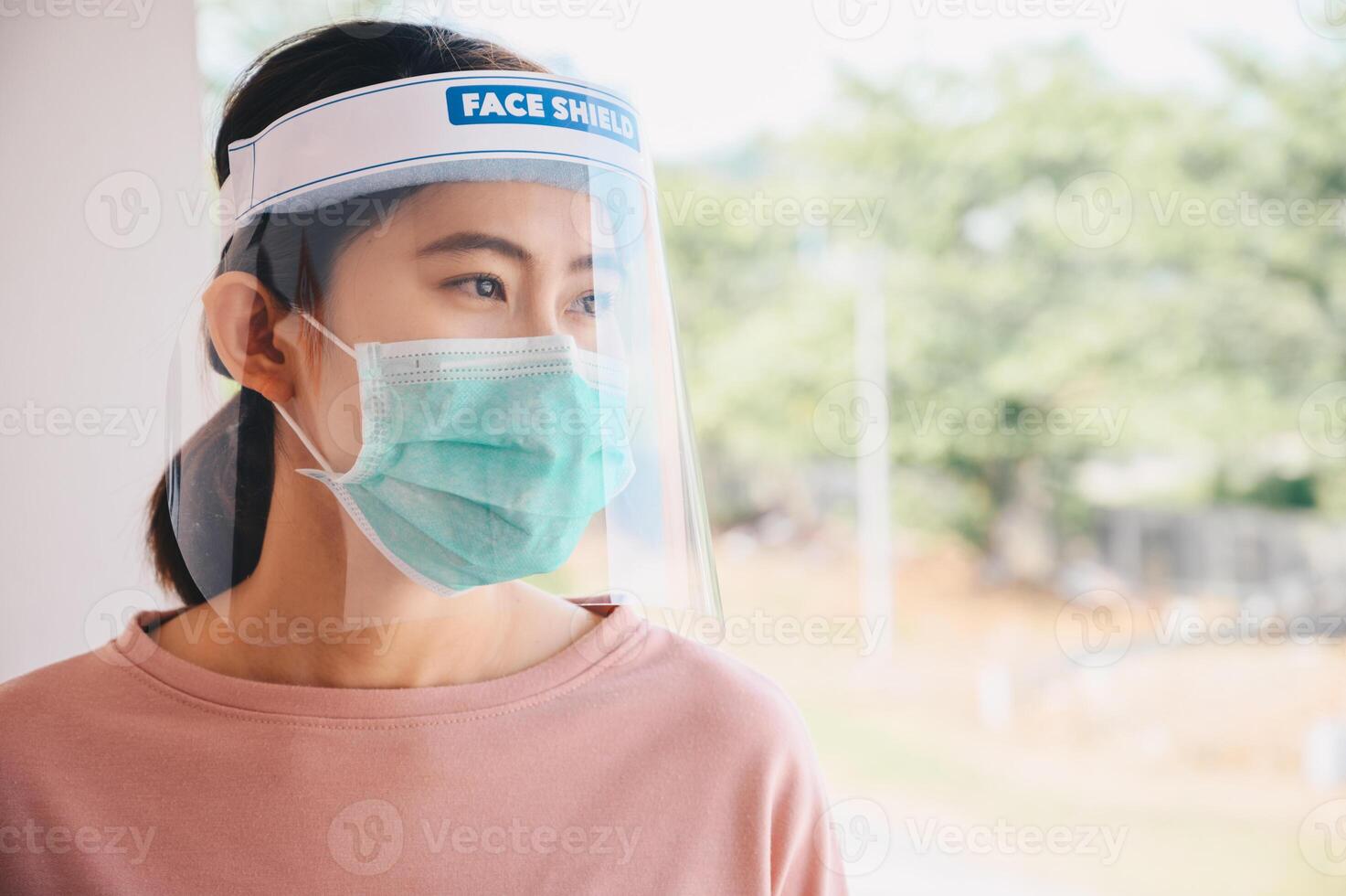 Asian woman wearing mask and face shield before going outside her room for prevent and protection covid-19 virus disease. Conceptual of new normal lifestyle after Covid-19 pandemic outbreak. photo