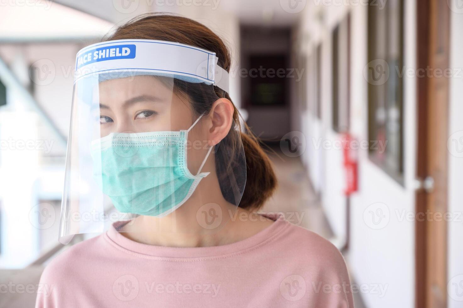 Asian woman wearing mask and face shield before going outside her room for prevent and protection covid-19 virus disease. photo