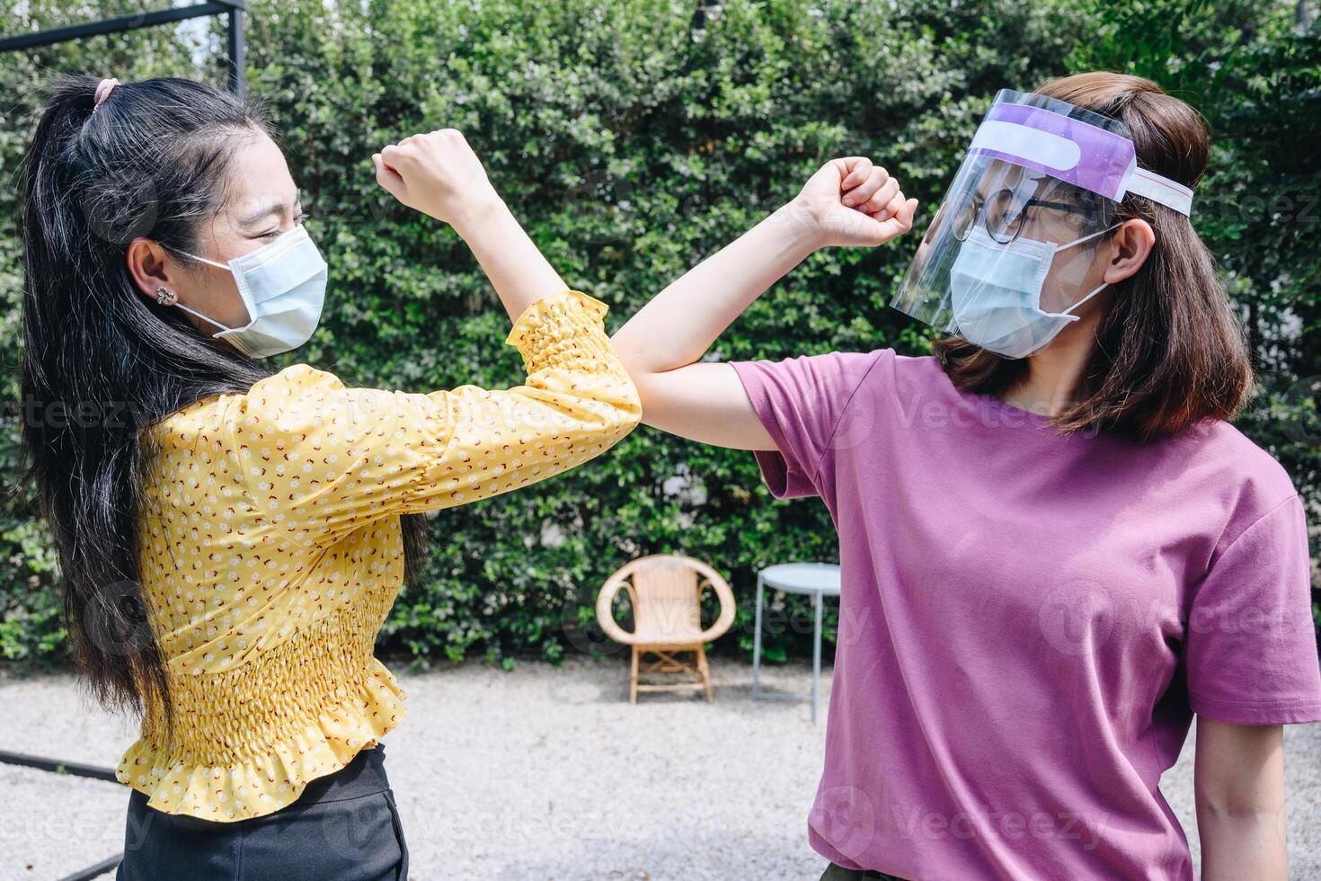Two woman bump elbows for greeting during coronavirus epidemic. The elbow bump was suggested as an alternative way for reduce your risk of spreading or contracting the virus. photo