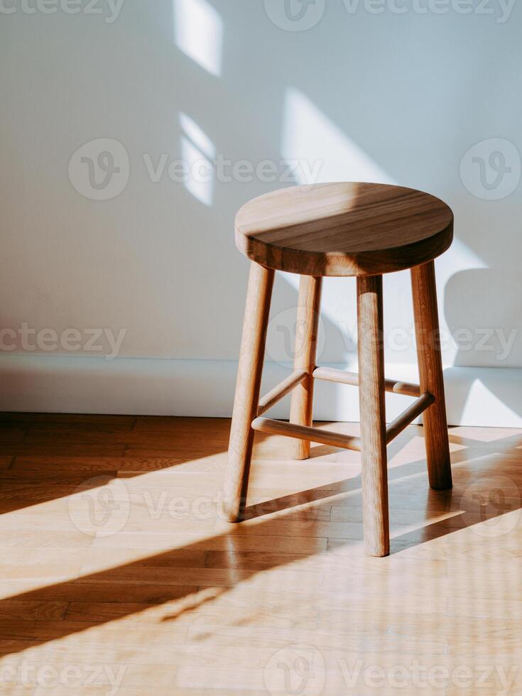 Brown wooden stool in room on parquet floor with shadows photo