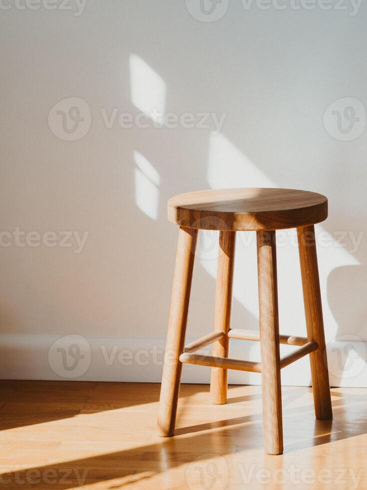 Brown wooden stool in room on parquet floor with shadows photo