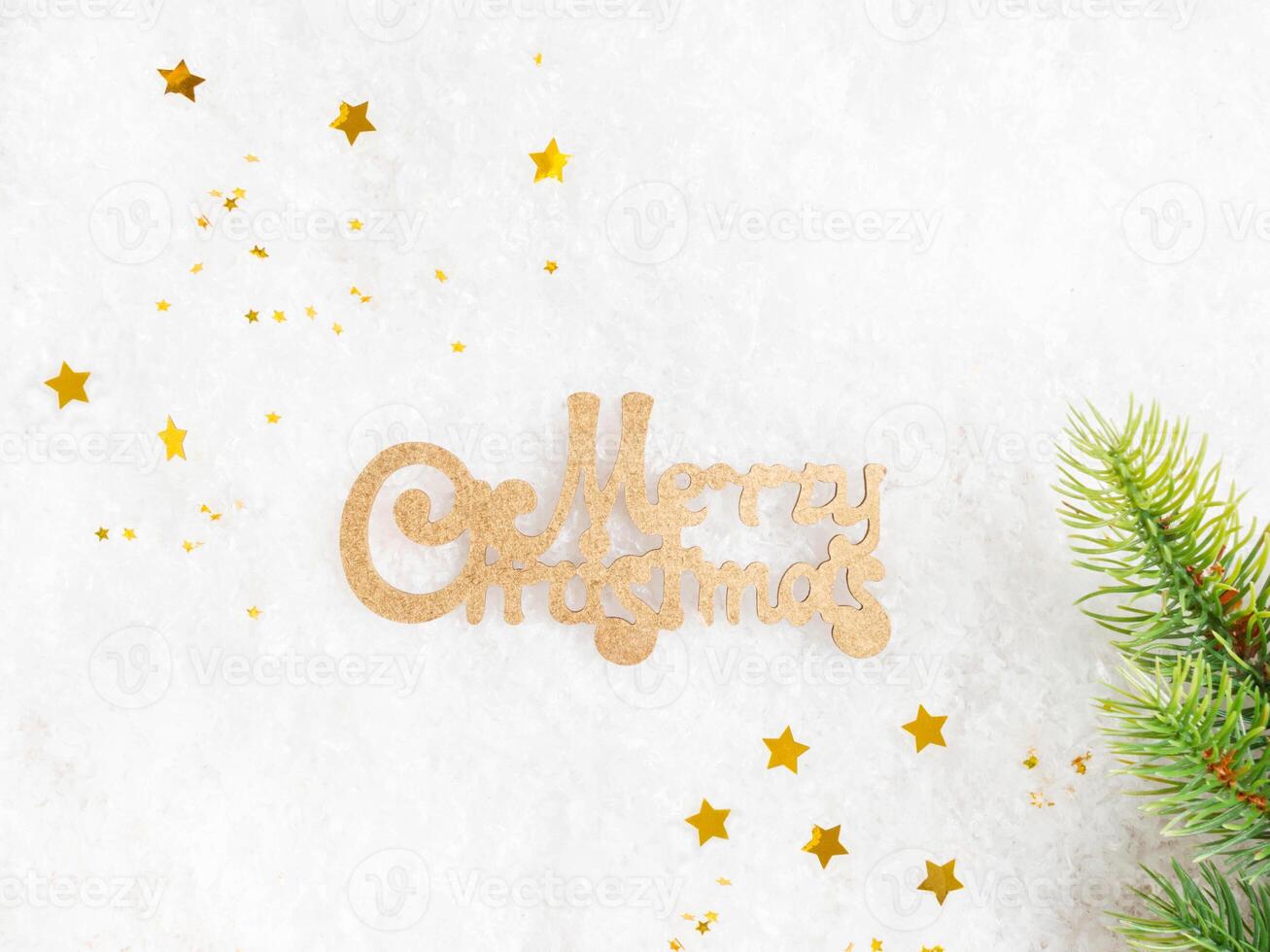 Flat lay frame various green and gold christmas decor and Wish you Merry Christmas on artificial snow background. photo