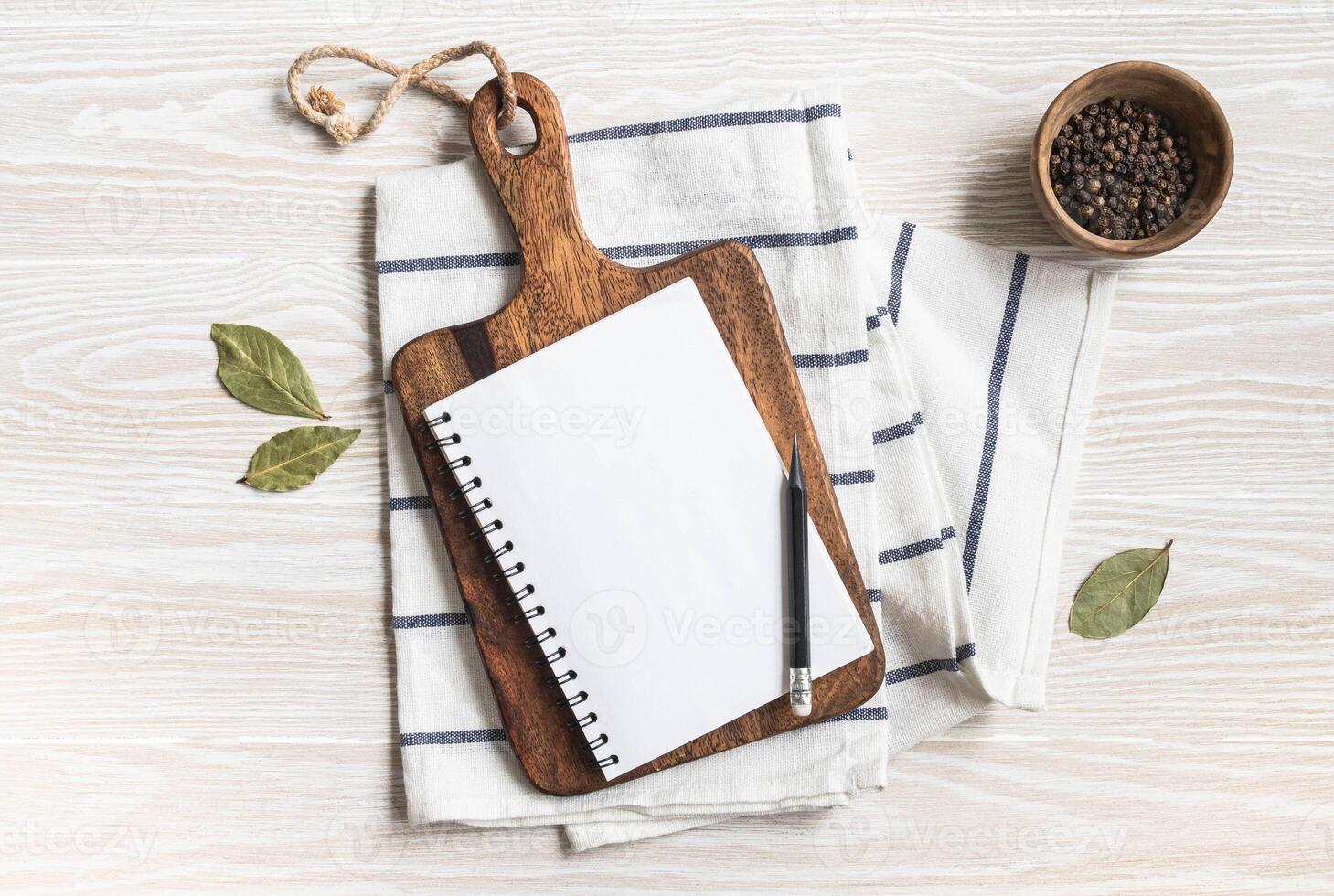 Minimal white kitchen background with blank notebook for text, cutting board, cotton napkin and various spices photo