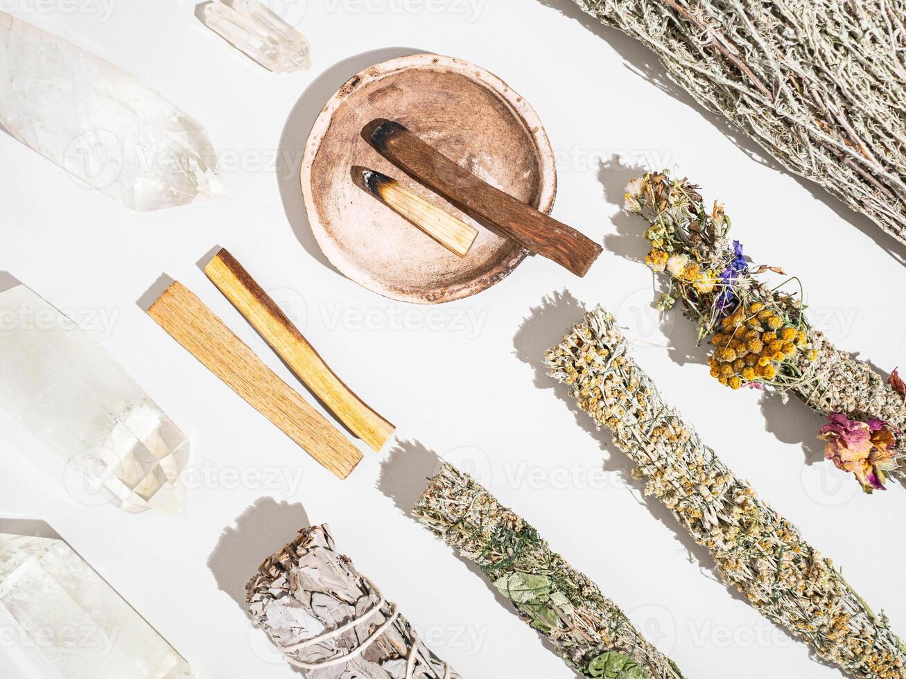 Items for spiritual cleansing - sage and aromatic herbs bundles, palo santo incense sticks and quartz crystals photo