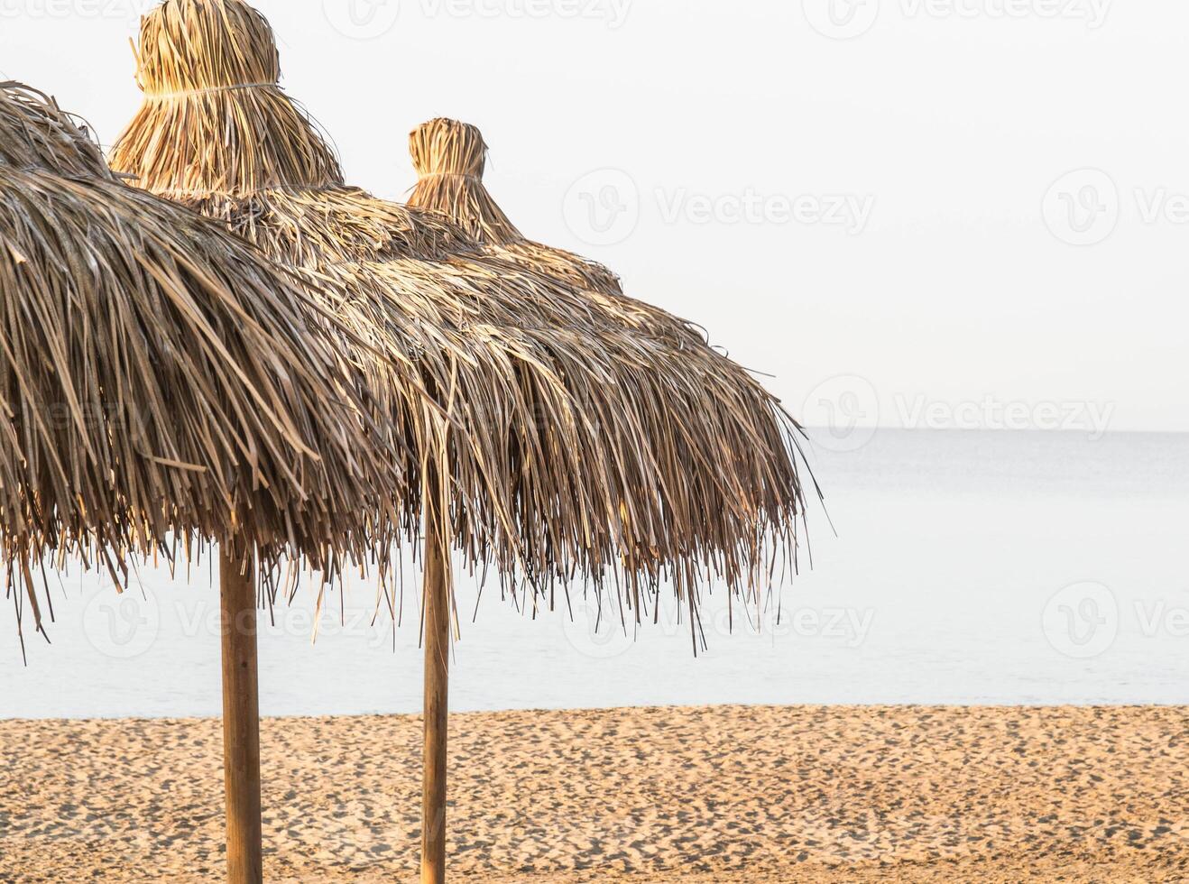 Straw umbrellas on empty seaside beach. photo