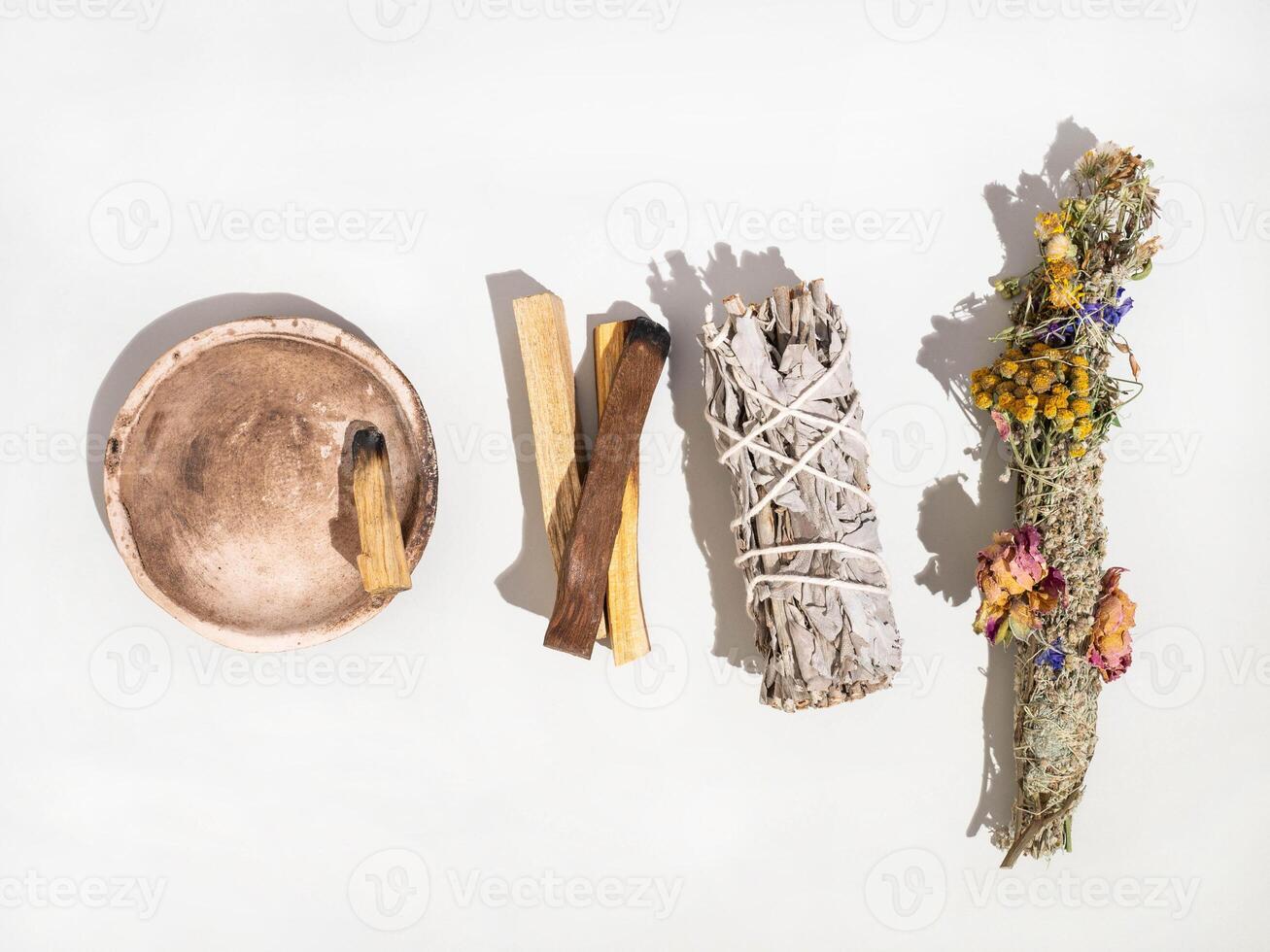 Items for spiritual cleansing - sage and aromatic herbs bundle and palo santo incense sticks on white background photo