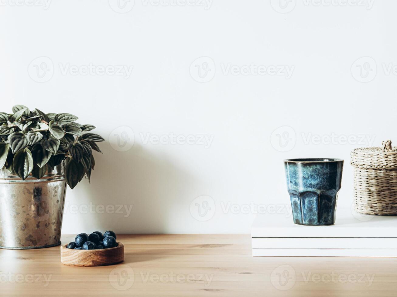 Minimalist concept of living room interior with houseplant in metal pot, magazines, glass with beverage and blueberries photo