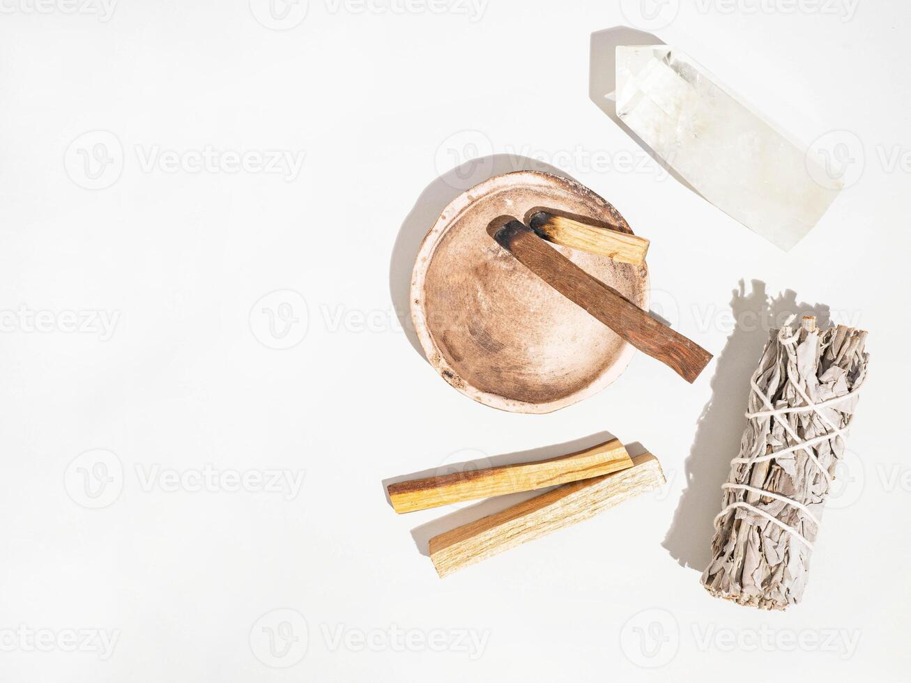 Items for spiritual cleansing - sage bundle, palo santo incense sticks and quartz crystal on white background. photo