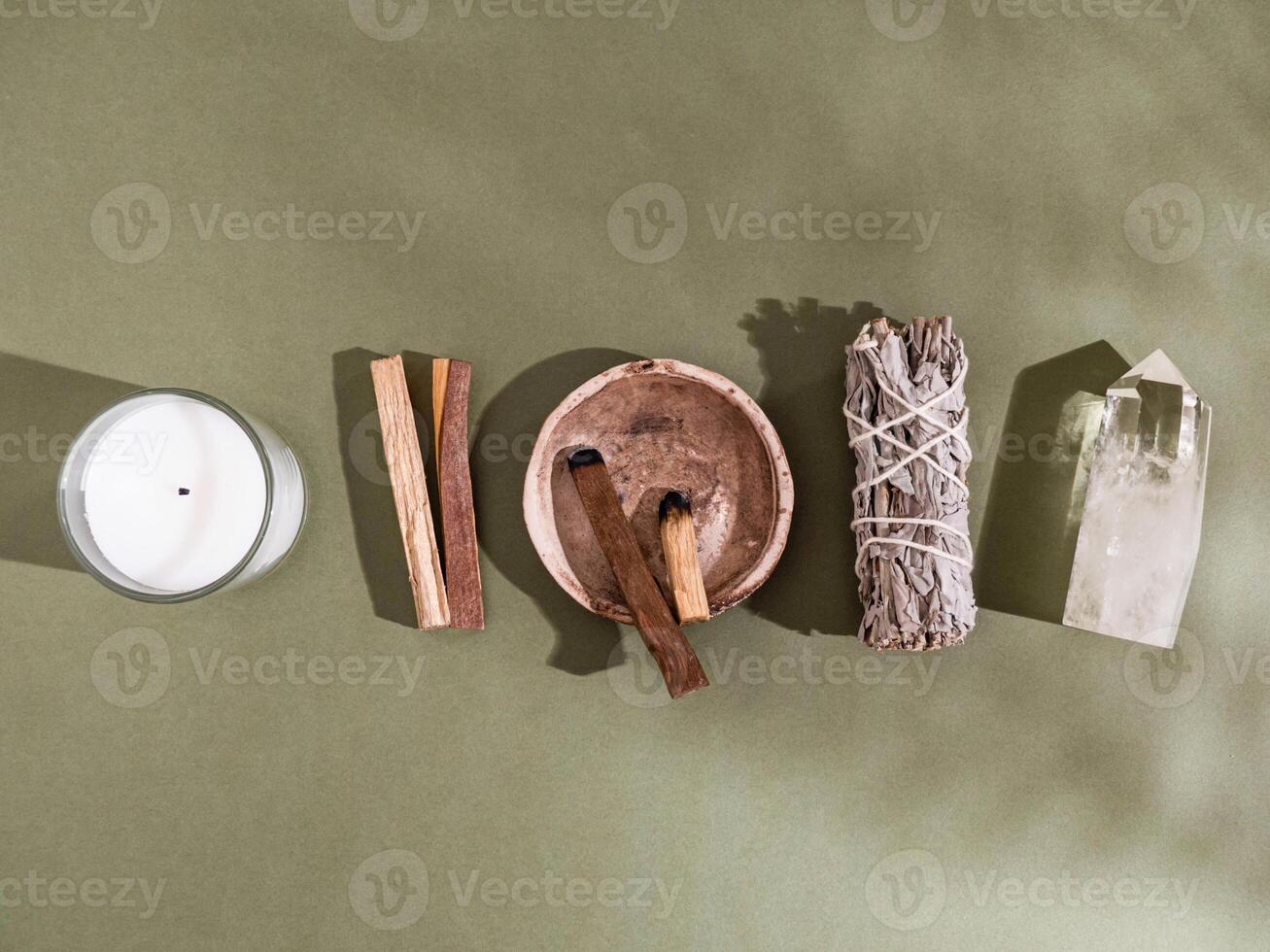Collection items for spiritual cleansing - sage bundle, palo santo incense sticks, candle and quartz crystal photo
