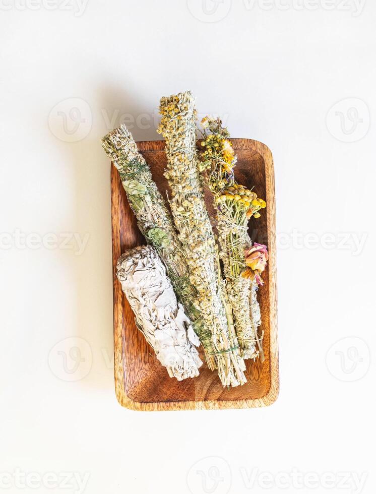 Herbs for spiritual cleansing - white sage and various aromatic herbs bundles on wood tray photo